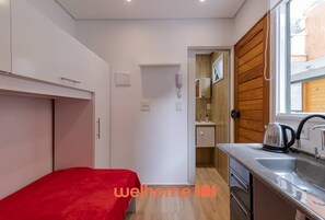 Ein kleiner Raum mit Bett, Küchenzeile und Bad.