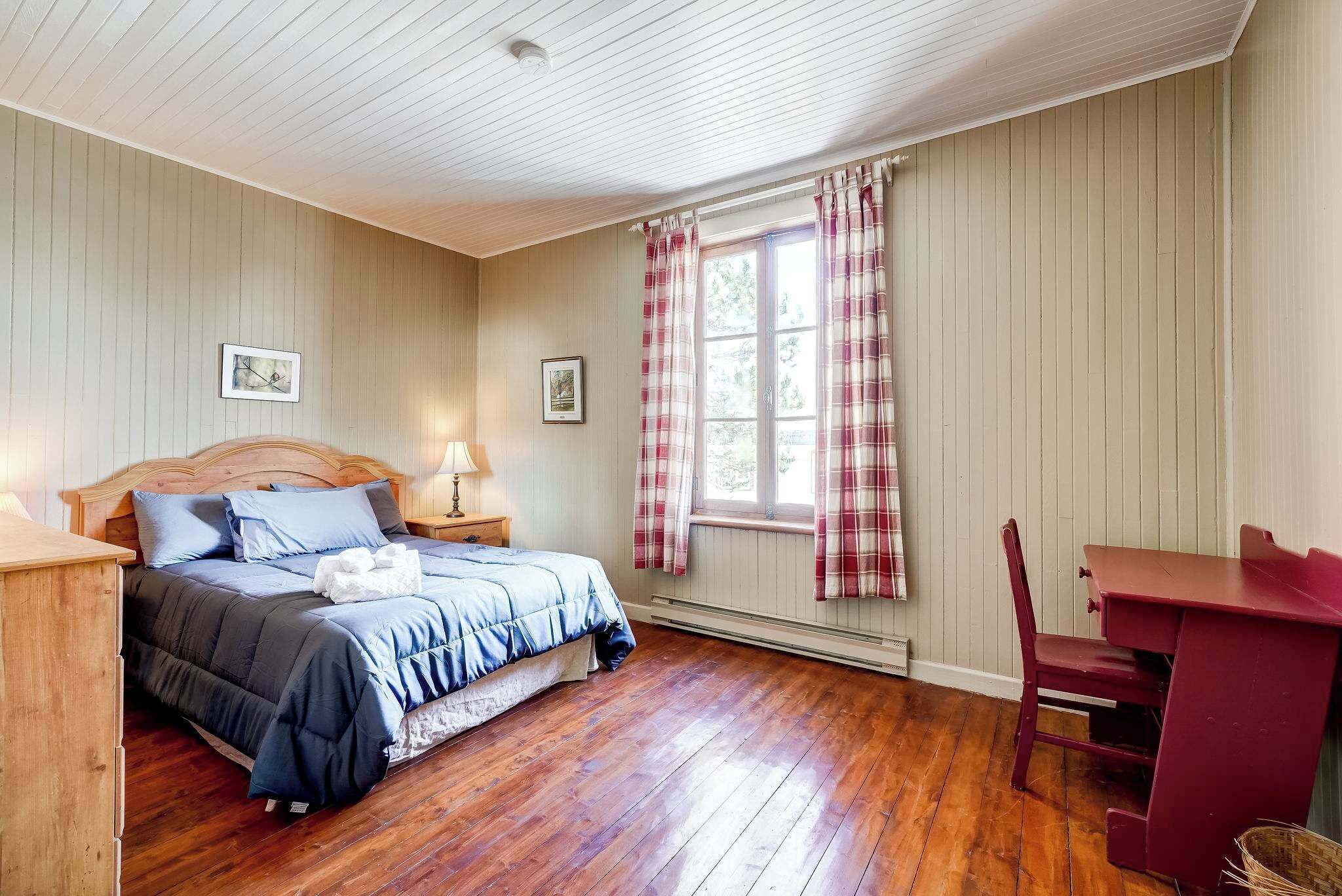 A bedroom with a wooden bed, a desk, and a chair.