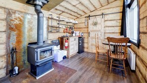Een rustiek houten chaletinterieur met een houtkachel, een eettafel en een stoel.
