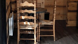 Interieur van een houten blokhut met een eettafel en stoelen, een hangspiegel en een deur met een esdoornbladmotief.