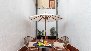 A small outdoor patio with a round table, two wicker chairs, a white umbrella, and a tiled floor. - Waou Urban Home Salamanca V (Madrid)