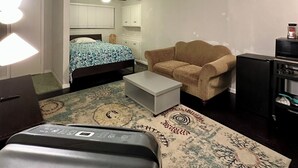 Un espacio habitable compacto con cama, sofá, una mesita y una zona de kitchenette.