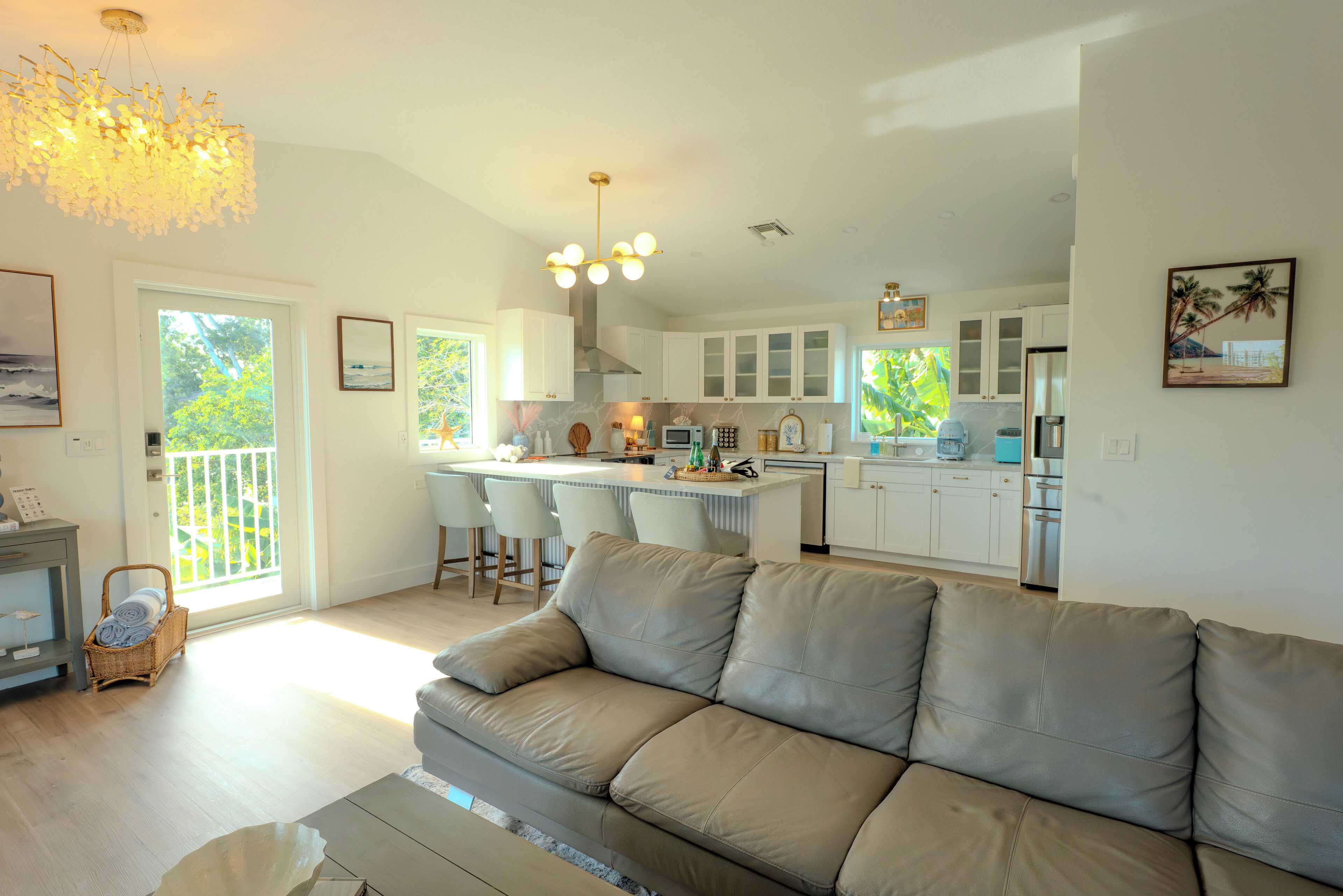 A modern kitchen with white cabinets, a central island, and a dining area with chairs.