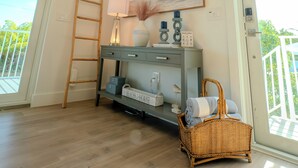 A bright room with a chandelier, a wooden ladder, a console table with decorative items, and a wicker basket.
