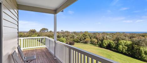 A covered porch with a view of a grassy landscape and trees.