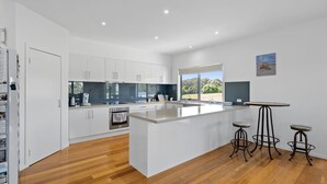 Una cocina moderna con muebles blancos, una isla grande y vistas al exterior.
