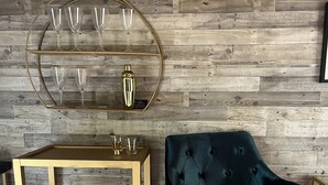 Ein Raum mit einer Holzwand, einer mit Gold gerahmten Glasvitrine, einem dunkelblauen Samt-Sessel und einem mit Gold gerahmten Beistelltisch.