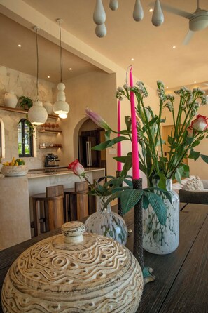 Et moderne køkken med en central ø, hængende lamper og en vase med blomster.