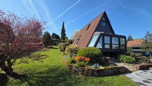 Ein modernes Haus mit Satteldach, einem großen Glasfenster und einem gepflegten Garten.