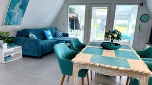 A modern living room with a sofa, chairs, a table, and a view through the glass door. - Villa Aurora - your retreat in nature (Waldbrunn)