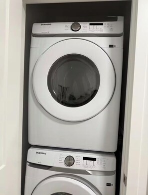 Eine gestapelte Samsung Waschmaschine und ein Whirlpool Trockner in einem Waschraum.