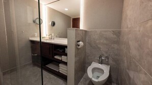 Une salle de bain moderne dotée d’une douche à parois de verre, de toilettes et d’un meuble-lavabo avec un miroir.