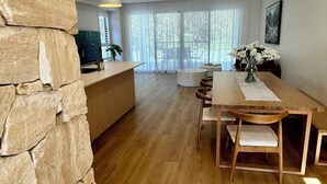Een moderne keuken met een accentmuur van steen, houten vloeren en een eethoek met een tafel en stoelen.