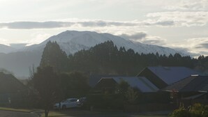 Ein Wohngebiet mit Häusern, einem Auto und einem Berg im Hintergrund.