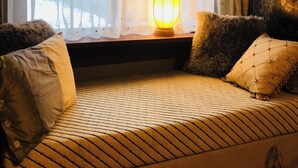 A cozy seating area with a patterned sofa, decorative pillows, and a warm lamp. - Cozy Nature-Inspired Feather Room With King Bed, Alcove Nook (Bigfork)