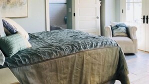 Un dormitorio con cama, una silla y una puerta.