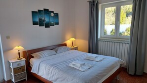 A neatly made bed with white linens and towels, a nightstand with a lamp, a wall art piece, and a window with curtains. - Marvelous 5-bedroom house with great terrace in Pješčana Uvala (Pješčana Uvala)