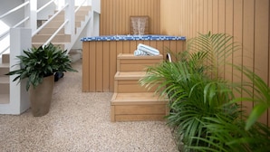 A modern outdoor area with a wooden staircase, a small pool with blue mosaic tiles, and potted plants. - Urban Beach House「UNIT #202「Palma」 (San Juan)