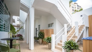 A modern interior with a staircase, seating area, and potted plants. - Urban Beach House「UNIT #202「Palma」 (San Juan)