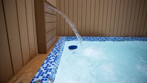 Ein Whirlpool mit einer Holzwand und blau gefliestem Boden.