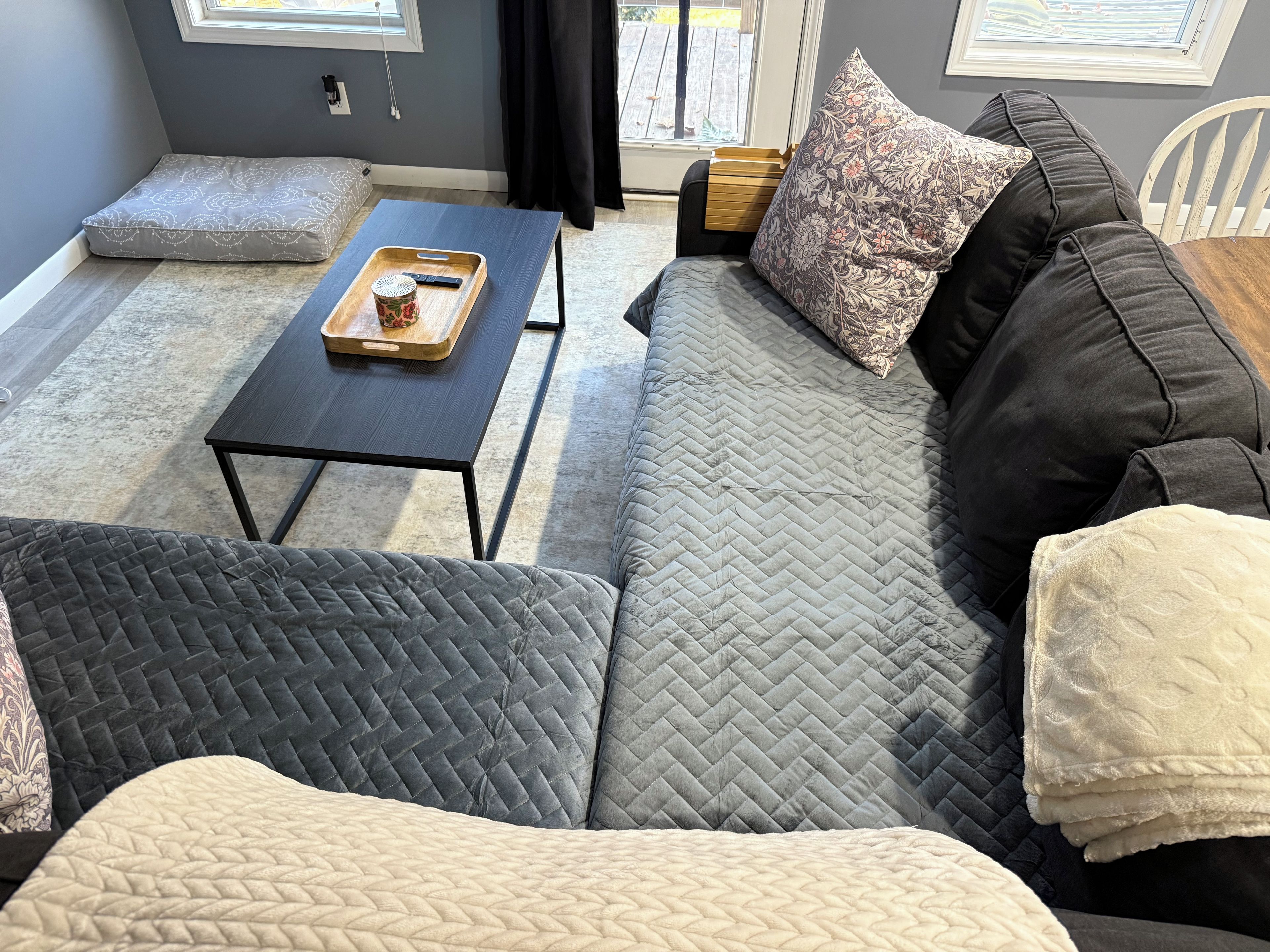 A modern living room with a sofa, a coffee table, and a window with curtains.