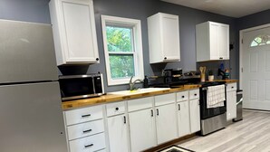A modern kitchen with white cabinets, a stainless steel refrigerator, a microwave, and a stove.