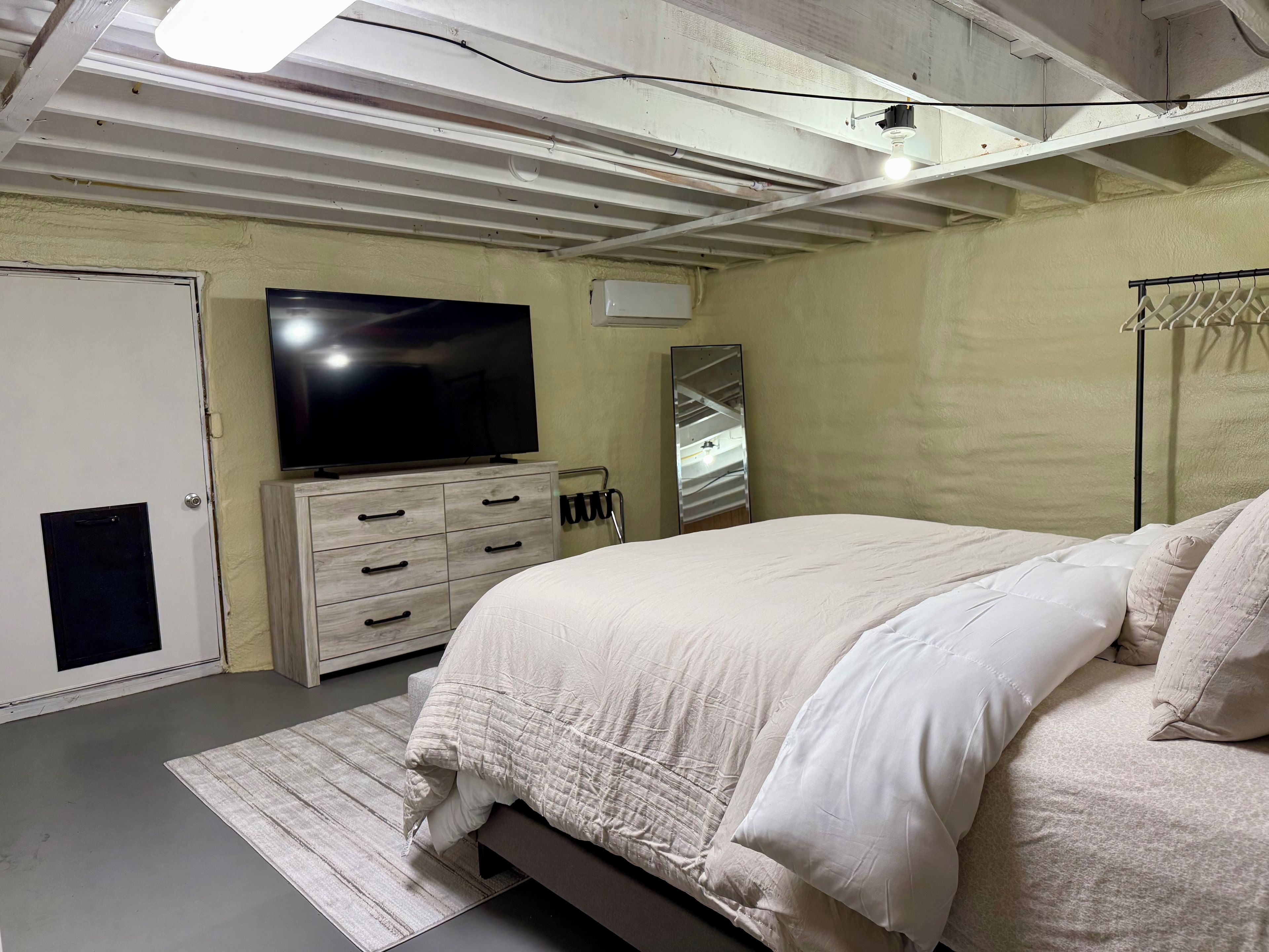 Un dormitorio con cama, cómoda, televisor, espejo y armario.