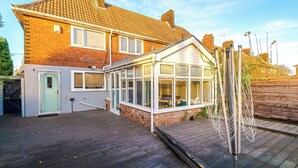 A residential property with a conservatory, a wooden deck, and a brick house. - Modern 3-Bed - Near Etihad & City Centre (Manchester)
