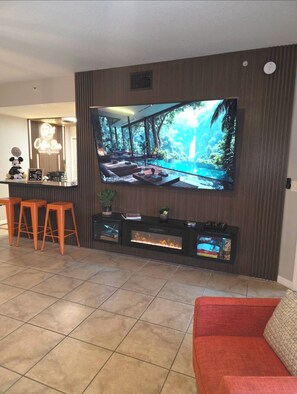 Stylish lounge with oversized TV, fireplace, and chic breakfast bar seating
