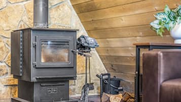 A wood-burning stove with a glass door, a chimney, and a log storage area.