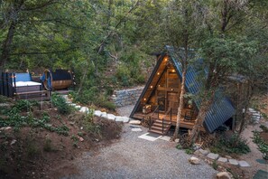 A cabin with a sloped roof, wooden deck, and a stone pathway leading to the entrance.