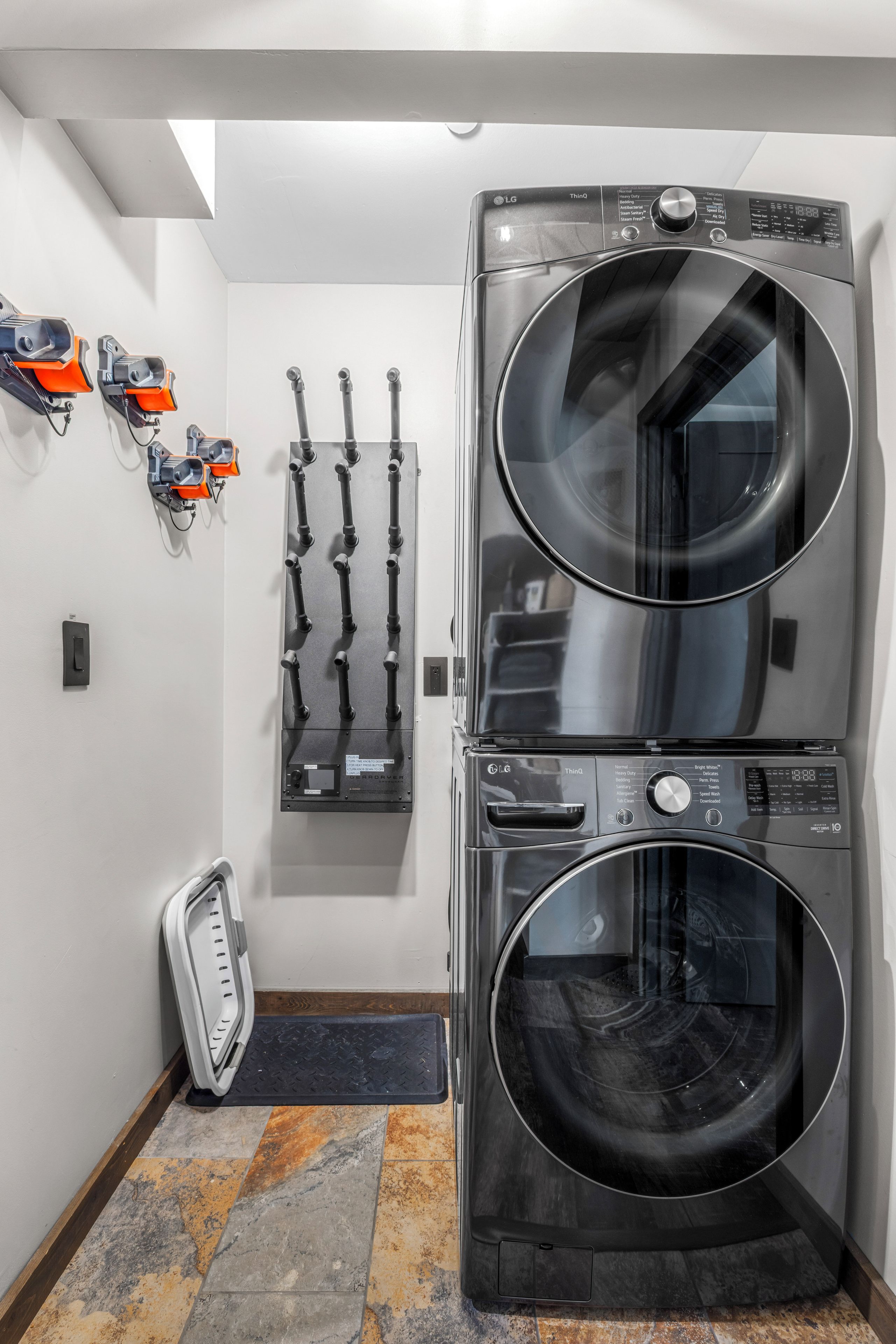 A laundry room with two stacked front-loading washing machines, a wall-mounted drying rack, and a scale.
