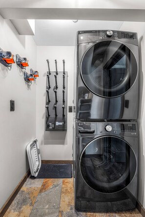 A laundry room with two stacked front-loading washing machines, a wall-mounted drying rack, and a scale. - Newly Remodeled A-Frame 5 min drive to Sundance (Sundance)