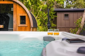 A hot tub with two glasses of amber liquid, a wooden barrel structure, and a small building in the background. - Newly Remodeled A-Frame 5 min drive to Sundance (Sundance)