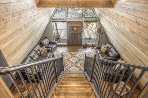 A spacious loft-style living area with a high ceiling, a wooden staircase, and a view of the outdoors through large windows. - Newly Remodeled A-Frame 5 min drive to Sundance (Sundance)