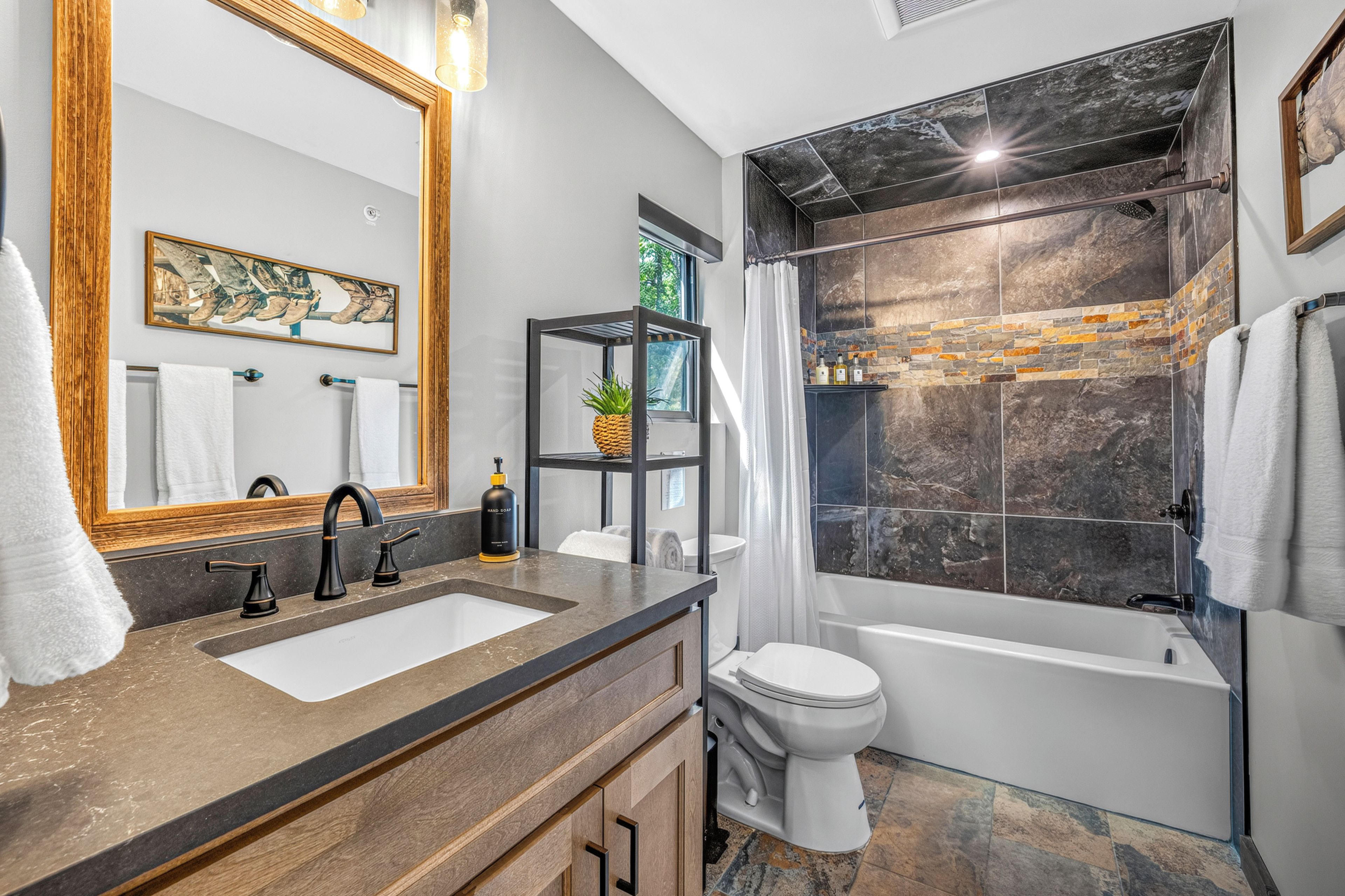 A modern bathroom with a large mirror, two sinks, a toilet, and a bathtub.