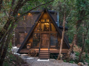 A cabin with a triangular roof, wooden exterior, and a porch with a wheelbarrow. - Newly Remodeled A-Frame 5 min drive to Sundance (Sundance)