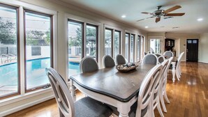 A dining area with a large table, chairs, and a view of a swimming pool. - Ocean Drive Grand Estate Sleeps 54 Pool (Corpus Christi)