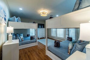 A room with bunk beds, a desk, and a lamp.