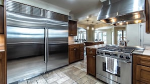 A modern kitchen with stainless steel appliances, wooden cabinets, and a central island. - Ocean Drive Grand Estate Sleeps 54 Pool (Corpus Christi)