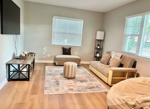 A modern living room with a sofa, ottoman, and a coffee table.
