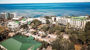 Ett flygbildsfoto av ett hotellområde vid kusten med flera byggnader, parkeringsplatser och utsikt över havet.