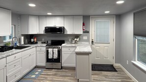 A modern kitchen with white cabinets, a stainless steel stove, and a microwave.