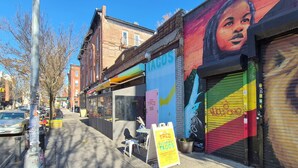 A street with a taco restaurant, a mural, and a closed shop.