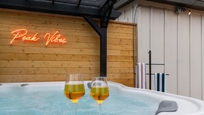 A hot tub with two glasses of wine, a neon sign reading "Peak Vibes", and wooden paneling in the background. - Ski Lodge, Ski Drop, Pickleball, HotTub, Sleeps 12 (South Salt Lake)