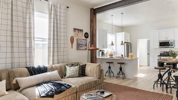 A modern living room with a sofa, coffee table, and a kitchen area with bar stools.