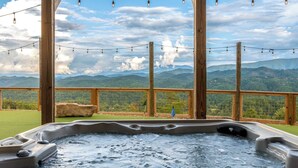 A hot tub with a view of mountains and a wooden deck with string lights. - 6BR for 26 | Pool, Hot Tub, Game Loft, & Mini Golf (Sevierville)