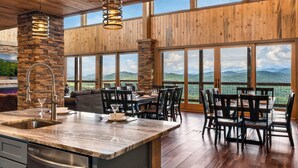 A spacious kitchen with a large island, a stone accent wall, and a view of the mountains. - 6BR for 26 | Pool, Hot Tub, Game Loft, & Mini Golf (Sevierville)