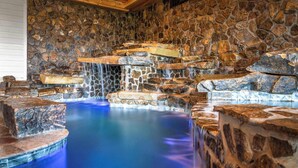 A stone-walled hot tub area with a waterfall feature. - 6BR for 26 | Pool, Hot Tub, Game Loft, & Mini Golf (Sevierville)