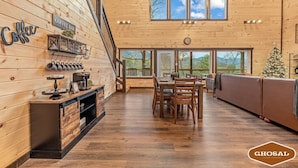 A wooden interior with a coffee bar, dining area, and large windows offering scenic views. - Summit Luxe Resort (Gatlinburg)